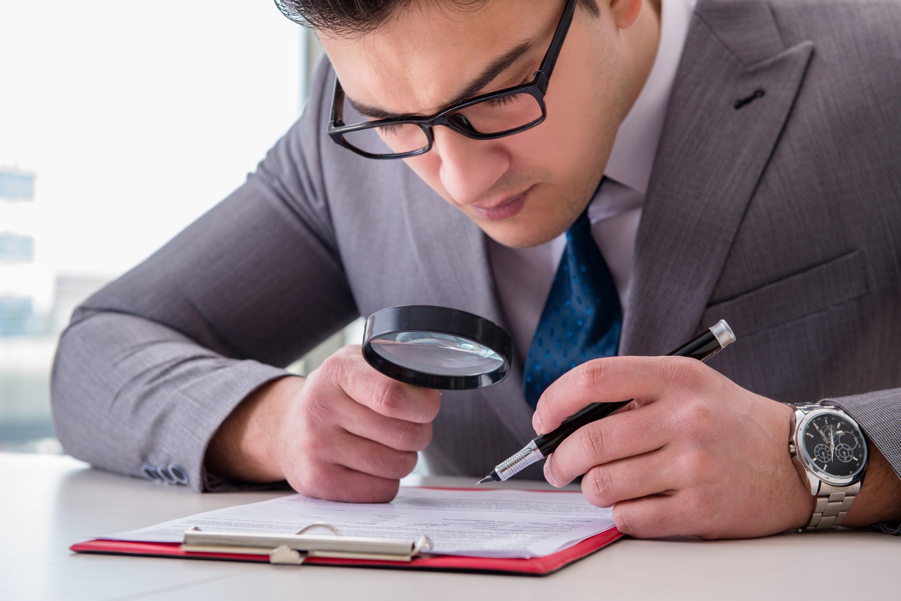 Businessman Reading Document with Magnifying Glass 